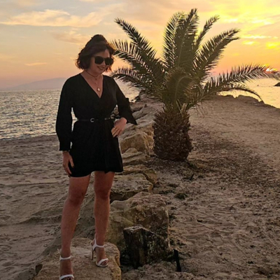 Cara Pepper, founder of Pepper Travel Co, standing on a rocky headland at sunset